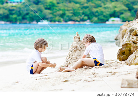 Two kid boys building sand castle on tropical Two kid boys building sand castle on tropical 30773774