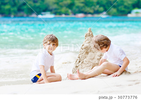 Two kid boys building sand castle on tropical Two kid boys building sand castle on tropical 30773776
