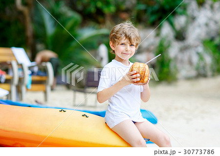Little kid boy drinking coconut juice on tropical Little kid boy drinking coconut juice on tropical 30773786