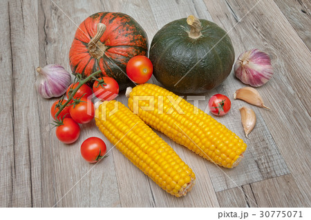 Vegetables lie on a wooden table. 30775071