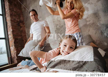 Amused little girl having pillow fight with 30778457