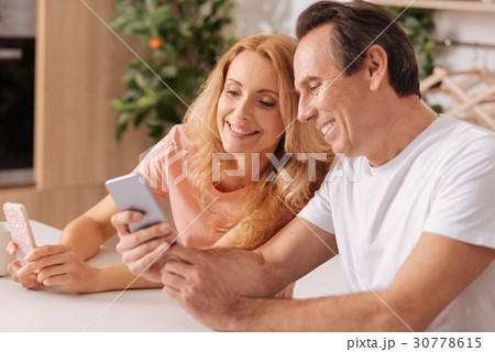 Positive mature couple using digital smartphones Positive mature couple using digital smartphones 30778615