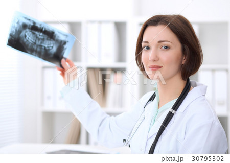 Young brunette female doctor sitting at the table 30795302