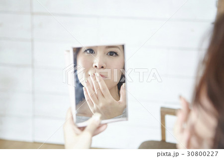 attractive lady using a mirror and touching her lips attractive lady using a mirror and touching her lips 30800227