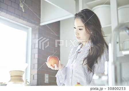 young lady standing in modern kitchen holding an apple young lady standing in modern kitchen holding an apple 30800253