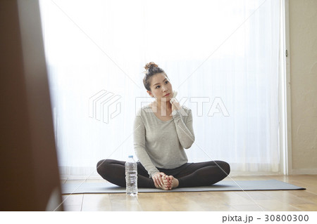 A woman is sitting and resting on the yoga mat. 30800300