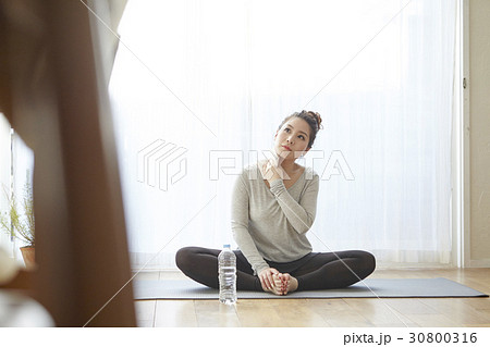 A woman is sitting and cleaning sweat after doing yoga exercise. A woman is sitting and cleaning sweat after doing yoga exercise. 30800316