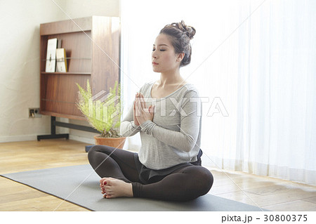 The woman is doing yoga exercise and meditation at home. 30800375