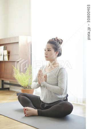A woman is doing yoga and meditation at home in the morning. A woman is doing yoga and meditation at home in the morning. 30800403