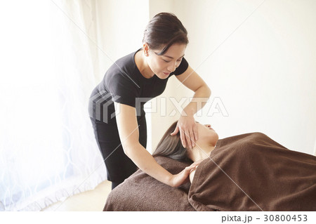 The therapist is massaging the neck of a woman. 30800453