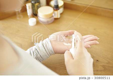 a woman is spraying cream on her hand. 30800511