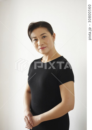 a portrait of a woman standing, holding hands and smiling. a portrait of a woman standing, holding hands and smiling. 30800560
