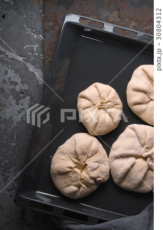 Khachapuri with cheese on a baking sheet on a Khachapuri with cheese on a baking sheet on a 30804312