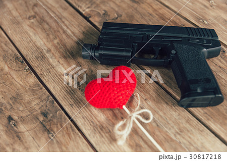 pistol gun and love red heart on wood background pistol gun and love red heart on wood background 30817218