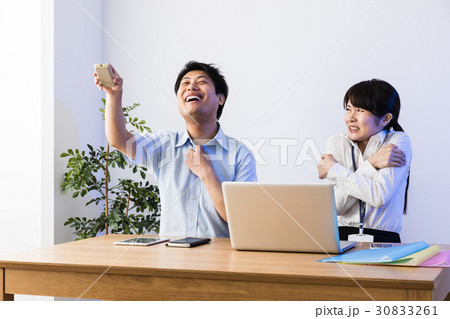 クーラーで涼むビジネスマンと凍えるビジネスウーマン、ノートパソコン 30833261