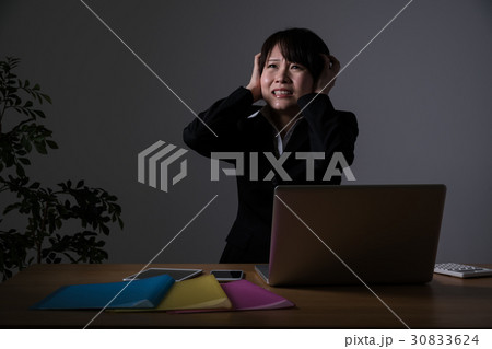 残業をするビジネスウーマン、頭を抱える 30833624