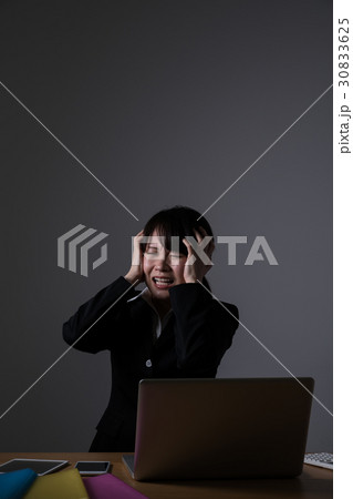 残業をするビジネスウーマン、頭を抱える 30833625