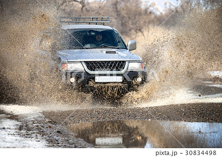Mitsubishi Pajero Sport on dirt road in early spring making spla 30834498