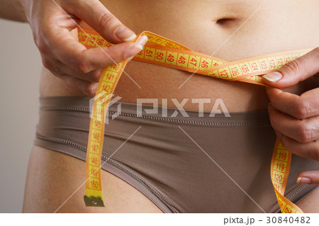 Woman measures a waist with a centimeter ribbon Woman measures a waist with a centimeter ribbon 30840482