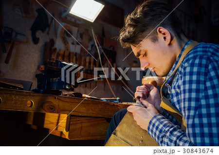 Master artisan luthier working on the creation of 30843674