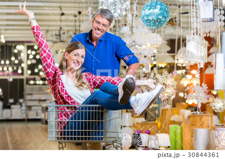 Man pushing woman in shopping cart trough hardware Man pushing woman in shopping cart trough hardware 30844361