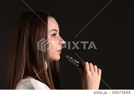 The face of vaping young woman at black studio The face of vaping young woman at black studio 30873688