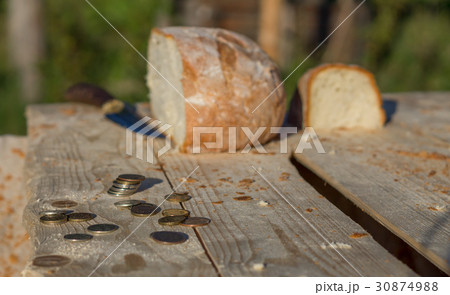 Bread on a table with coins and knife 30874988