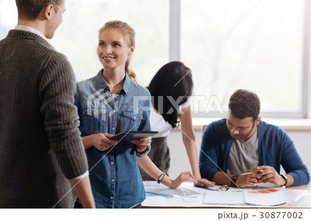 Joyful positive woman talking to her colleague 30877002