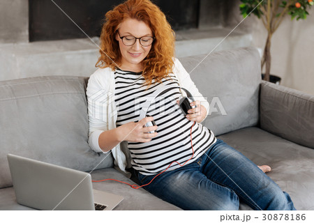 Beautiful expectant mother putting headphones over 30878186