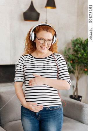 Cheerful woman smiling and holding hands on belly Cheerful woman smiling and holding hands on belly 30878191