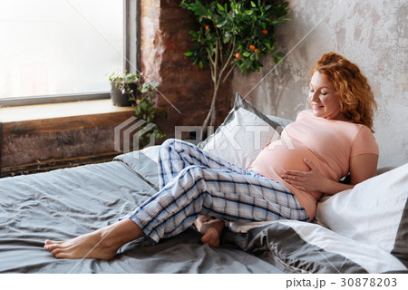 Prospective mom in pajama looking on baby bump 30878203