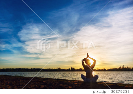 Young woman doing yoga exercises on the lake beach Young woman doing yoga exercises on the lake beach 30879252