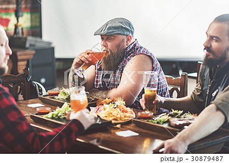 Three mature males drinking lager in pub 30879487