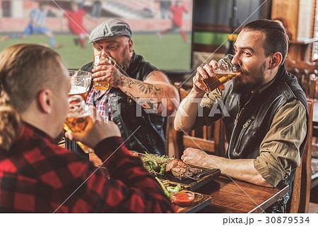 Three bearded guys enjoying beer in pub 30879534
