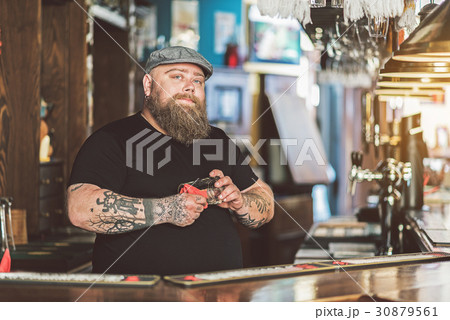 Fat bartender wearing cap laboring in pub 30879561