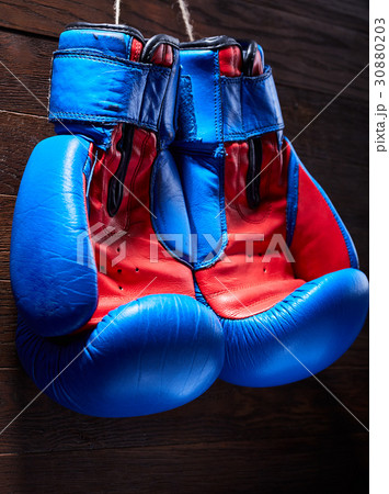 A pair of red and blue boxing gloves hang against 30880203