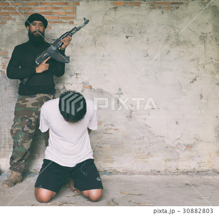 Terrorist in balaclava threatening with gun to man 30882803