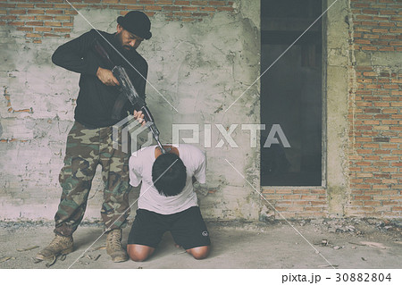 Terrorist in balaclava threatening with gun to man 30882804