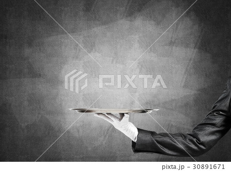 Hand of butler holding empty metal tray against concrete background 30891671