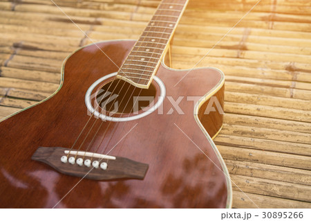 Acoustic guitar placed on a wooden table Acoustic guitar placed on a wooden table 30895266