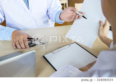 Two doctors discussing patient notes in an office pointing to a 30896934