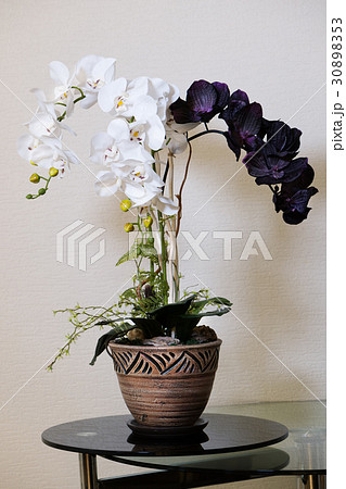 Artificial orchids flowers in old fashion flower pot on glass table. 30898353
