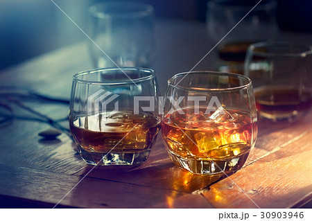 Whiskey bourbon glasses with ice on wooden table 30903946