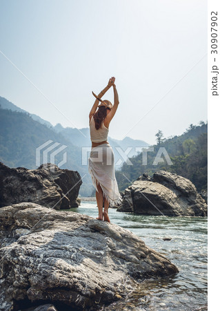 Woman do yoga pose on a bank of Ganga river Woman do yoga pose on a bank of Ganga river 30907902