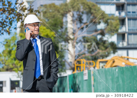 Man architector outdoor at construction area having mobile conversation 30918422