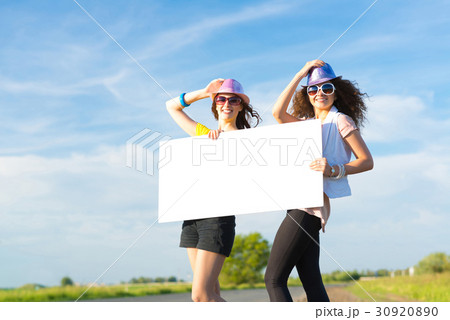 Two young women stand with a blank banner 30920890