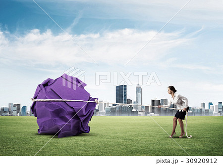 Woman pulling with effort big crumpled ball of paper as creativity sign 30920912