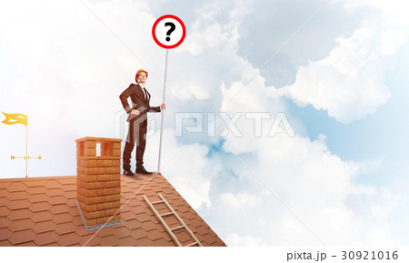 Businessman on brick house roof showing banner with question mark. Mixed media 30921016
