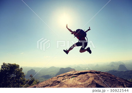 successful woman hiker jumping on mountain peak 30922544