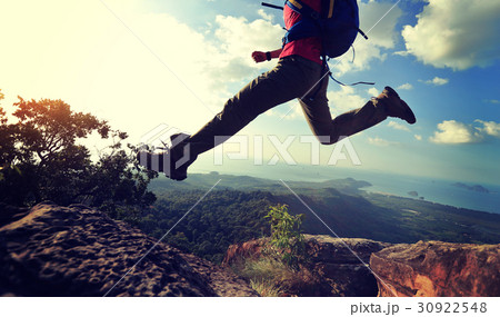 young woman hiker jumping on mountain peak 30922548